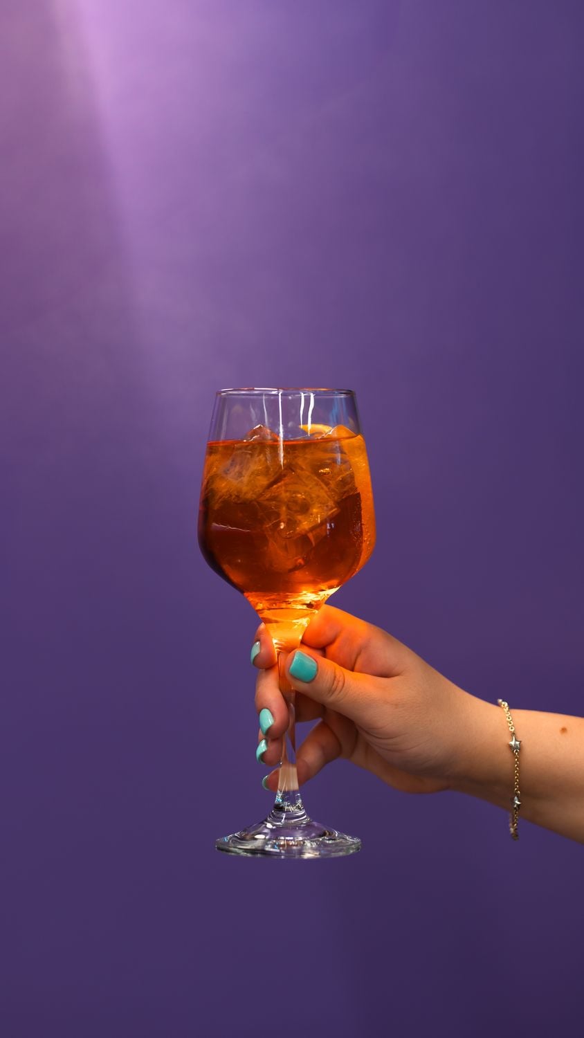 Ένα Aperol spritz σε ποτήρι κρασιού μπροστά από μωβ φόντο